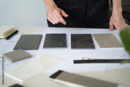 The interior designer selects ceramic stoneware and marble samples. Designer at work. Interior design. Architecture. Decoration. Design project blueprints. Grey marble. Grey stone. Decorative material