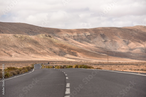 An empty road on Fuerteventura countryside, with volcanic mountains in the background