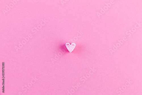 Pink background with one little heart. The concept of minimalism. Love card, Valentine's day, Mother's day, Birthday.