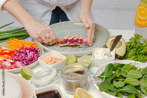 Woman's hands carefully rolling the spring roll with shrimps. Appetizing shot of asian dish.