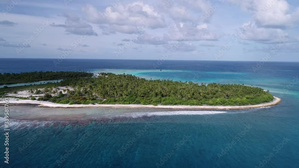 Beautiful drone shot of the Tuheiava Pass in Tikehau, French Polynesia. Blue cloudy sky and a small island with palm trees and pink sand flank the lagoon. Coral reef breaks in the distance Beautiful drone shot of the Tuheiava Pass in Tikehau, French Polynesia. Blue cloudy sky and a small island with palm trees and pink sand flank the lagoon. Coral reef breaks in the distance