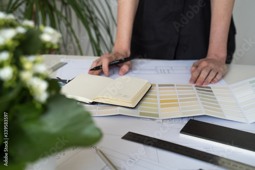 The interior designer selects wall paint samples. Designer at work. Architect desk. Decoration. Design project blueprints. Plans and drawings. Grey stone. Paint catalog. Decorative material. Flatlay