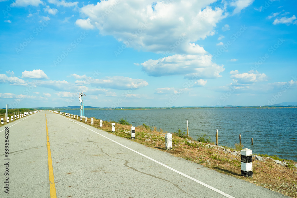 Obraz premium Blue clouds sky and ahead long empty asphalt with black and white concrete kilometre sign pole along seaside road ,blue sea mountain landscape in sunny day in Thailand.