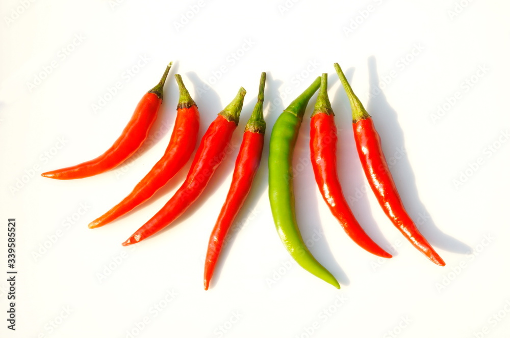 In the photo, red and green chili peppers. Seven pods on a white background.