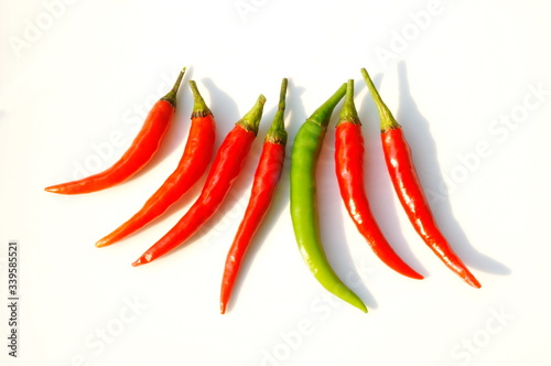 In the photo, red and green chili peppers. Seven pods on a white background.