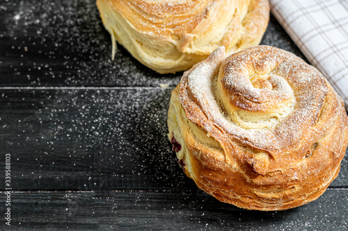 Bakery products with raisins and dried fruits are located on a dark wooden background. Sprinkled with icing sugar. Kraffins. Easter food. photo