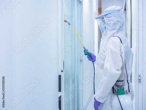 Asian women wear personal protective suits or PPE, goggles, masks, and gloves making disinfection and decontamination on public place.. to reduce spreading of disease. Covid-19, coronavirus concept