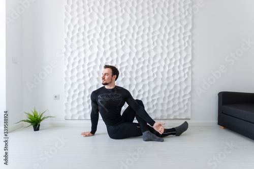 Stretching Instructions. Home fitness. COVID-19 concept. Exercises for all muscle groups. Muscular man demonstrates gymnastic exercises. Twisting the spine while sitting on the floor.