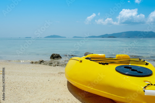 Yellow kayak boat on beautiful beach with ocean and sky background
