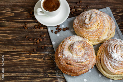 Bakery products with raisins and dried fruits are located on a dark wooden background. Sprinkled with icing sugar. Kraffins. Easter food. photo