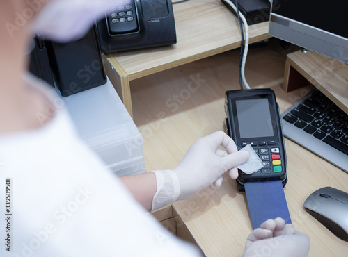 Asian women at cashier counter use alcohol pad to clean credit card terminals or machine before swiping client card, prevent spreading of coronavirus. Covid-19, coronavirus, social distance concept.