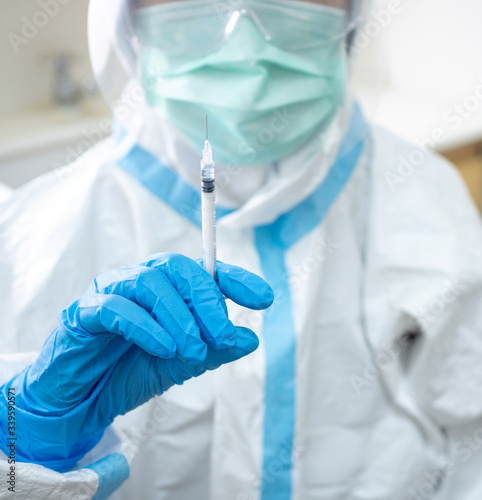 Woman doctor in personal protective suit prepare vaccine shot to stimulating immunity of patient at risk of coronavirus infection. Coronavirus, covid-19, medical and vaccination concept.