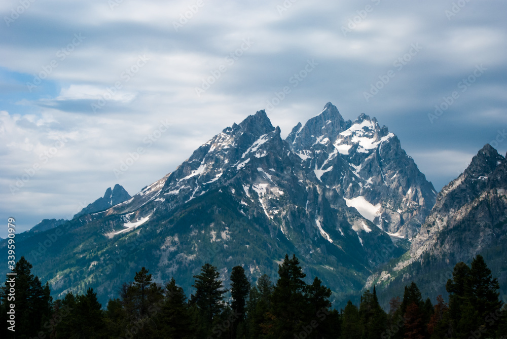 Mountains in the Teton range rising over the dark forest at their base