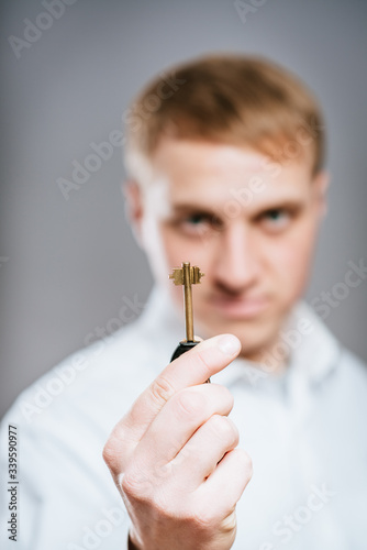 Man wearing a  shirt looking happy holding a rusty key.