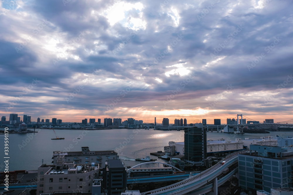 Scenic cityscape view in tokyo japan with beautiful dramatic sky and sunlight through clouds at sunrise time in the morning.