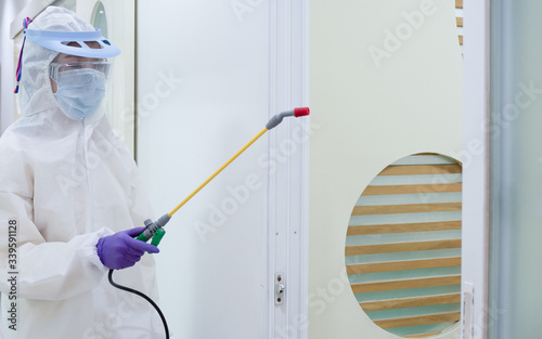 Asian women wear personal protective suits or PPE, goggles, masks, and gloves making disinfection and decontamination on public place. to reduce spreading of disease. Covid-19, coronavirus concept