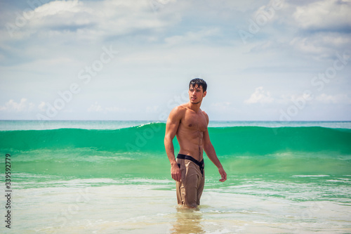 Handsome young man standing on a beach in Phuket Island, Thailand, shirtless wearing boxer shorts, showing muscular fit body © theartofphoto