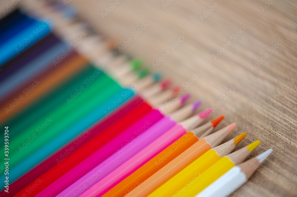 Fototapeta premium Rainbow of colored pencils on wood background