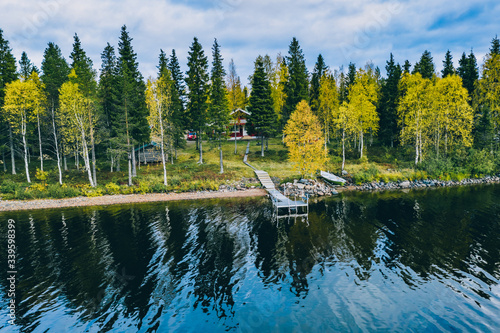 Aerial top view of log cabin or cottage with sauna in spring forest by the lake in Finland