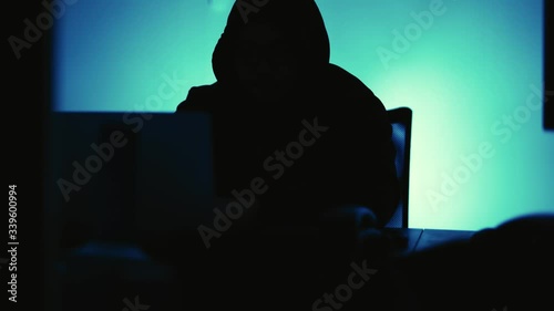 A computer programmer or hacker prints a code on a laptop keyboard to break into a secret organization system.