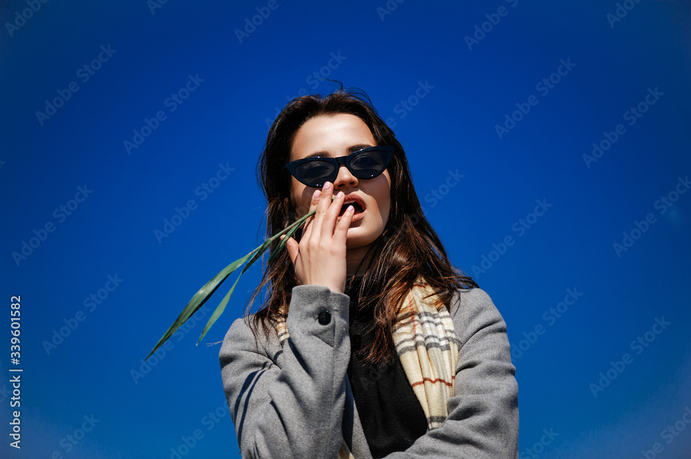 Fashionable attractive young girl posing on the road. Portrait against a clear blue sky Fashionable attractive young girl posing on the road. Portrait against a clear blue sky
