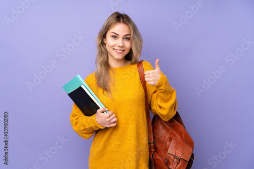 Teenager Russian student girl isolated on purple background showing ok sign and thumb up gesture