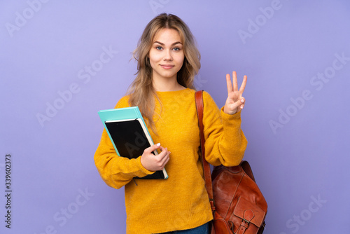 Teenager Russian student girl isolated on purple background happy and counting three with fingers