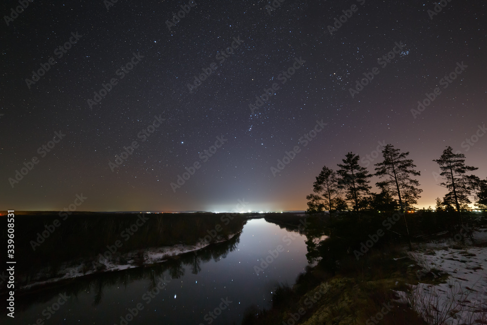 Bright stars of the night sky over the river. Landscape with a view of outer space.
