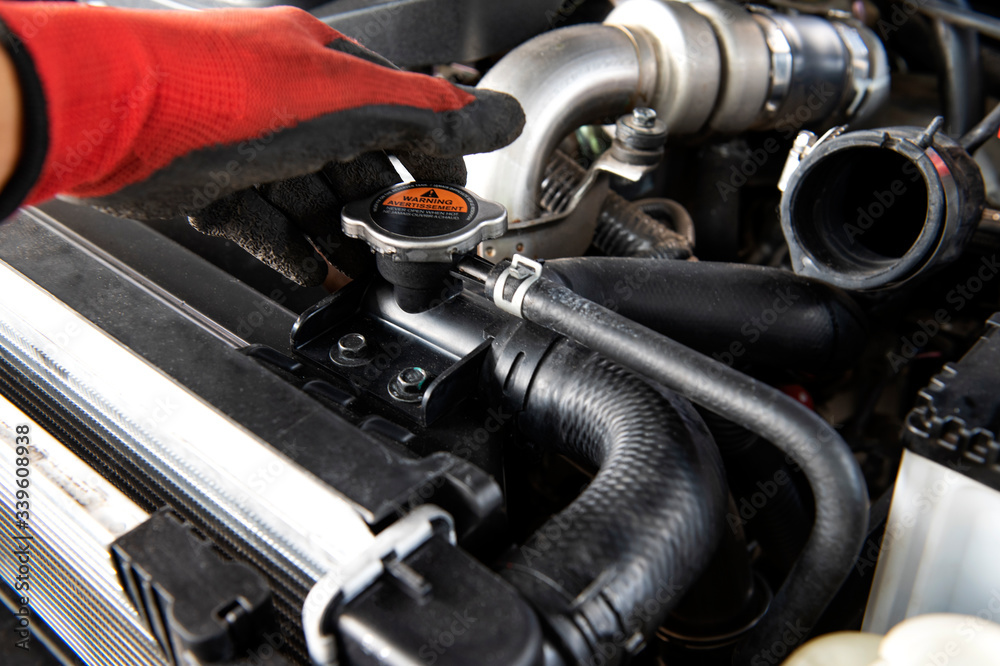 Fototapeta premium Mechanic check the radiator car. Hands of mechanic working in auto repair garage. Check and maintenance the water in radiator car with yourself. Service and maintenance vehicle.
