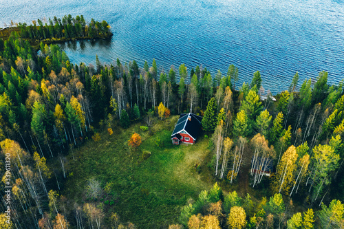 Fotografia Aerial top view of red log cabin or cottage with sauna in spring forest by the l