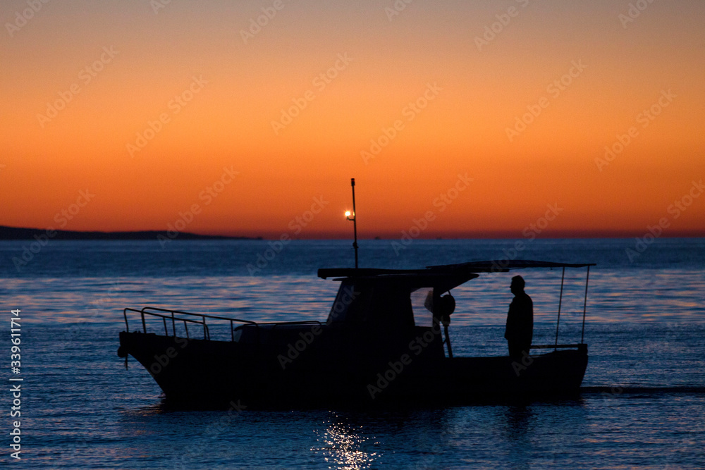 Silhouette of a fishermen sailing in the sunrise