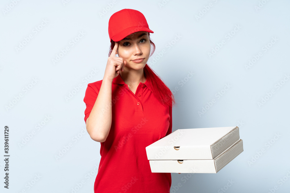 Pizza delivery girl holding a pizza over isolated background thinking an idea Pizza delivery girl holding a pizza over isolated background thinking an idea