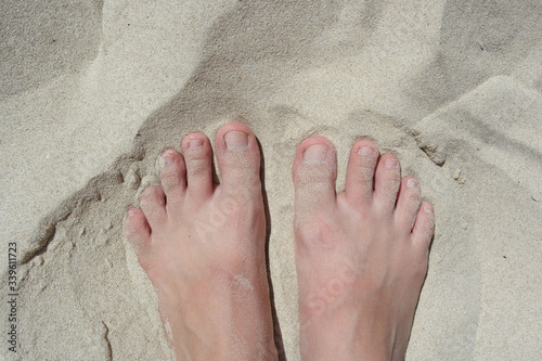 White sand texture female legs. white legs without shoes on the hot white sand. Bare feet of a girl on the beach. Smooth sunny sandy beach