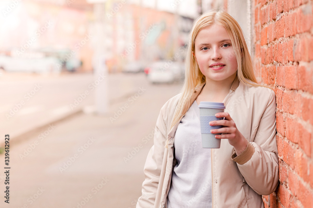 Portrait of young caucasian woman holding a cup of coffee against brick wall. Urban concept. Portrait of young caucasian woman holding a cup of coffee against brick wall. Urban concept.