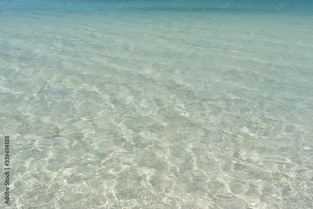 Transparent turquoise sea water, natural background. Sea surface in a turquoise lagoon. The texture of sea water. Summer and travel vacation concept.