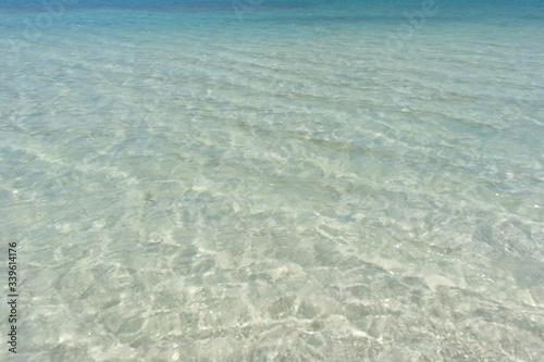 Transparent turquoise sea water, natural background. Sea surface in a turquoise lagoon. The texture of sea water. Summer and travel vacation concept.