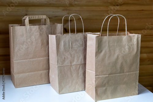 Three brown carton paper bags with handles on the wooden background