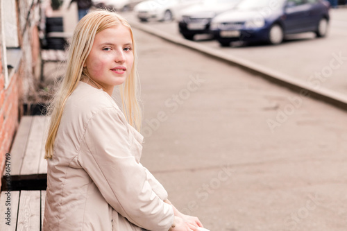 Beautiful blonde girl sitting on a bench and posing for the camera