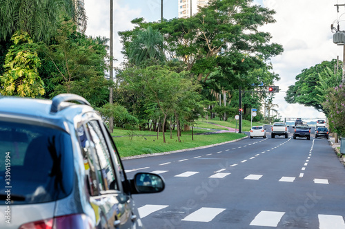 One way avenue with four lanes, large wooded avenue with few traffic of cars. Car stopped before the pedestrian crossing lane. Afonso Pena avenue at Campo Grande MS, Brazil. © Vinícius Bacarin