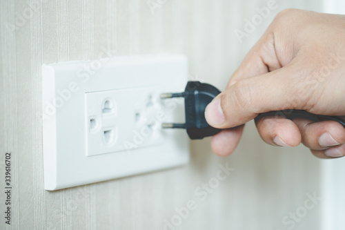 image of black plug in electric socket on wall.