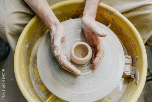 hands make a vase behind a potter's wheel. ceramics. pottery, macro shooting