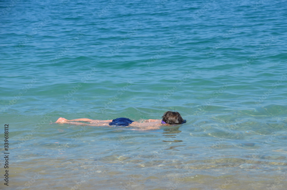 The boy in a horizontal position lies on the water in the sea.