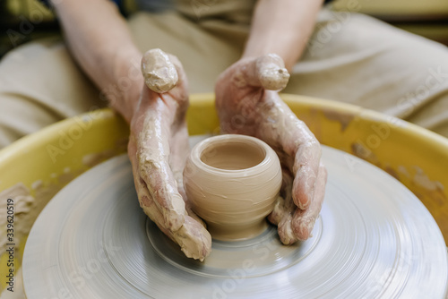 hands make a vase behind a potter's wheel. ceramics. pottery, macro shooting