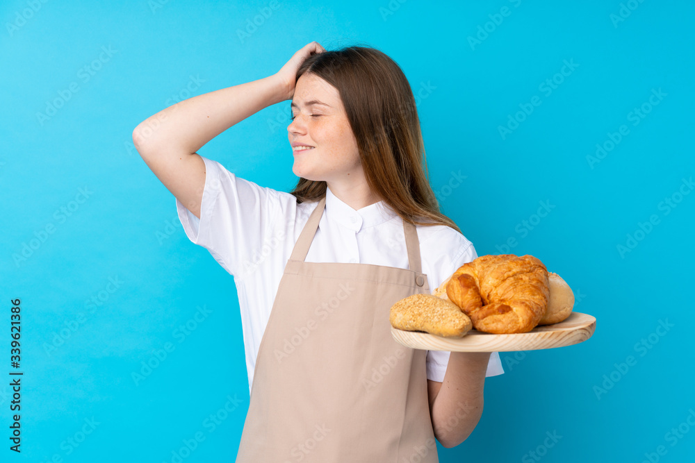 Ukrainian teenager chef uniform. Female baker holding a table with several breads has realized something and intending the solution Ukrainian teenager chef uniform. Female baker holding a table with several breads has realized something and intending the solution