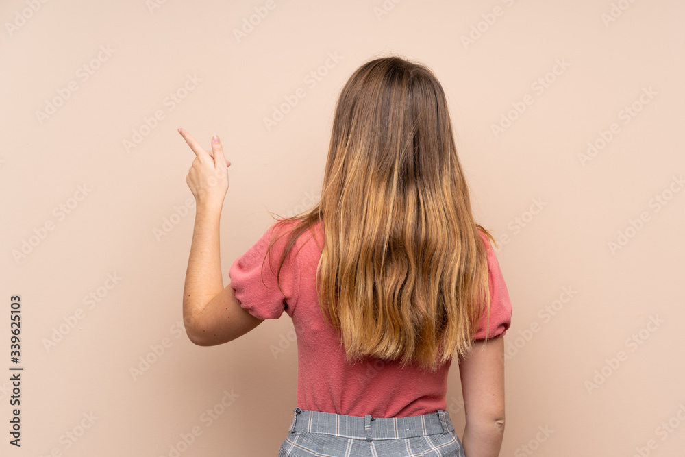 Ukrainian teenager girl over isolated background pointing back with the index finger Ukrainian teenager girl over isolated background pointing back with the index finger