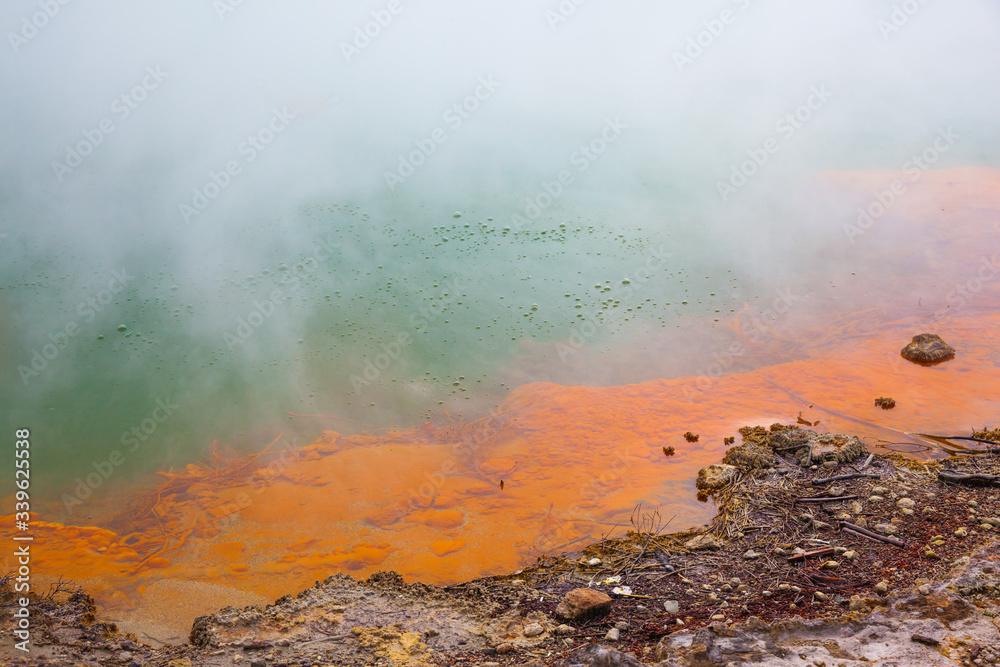 Hot lake with gas bubbles and orange shore
