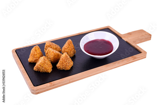 Camembert cheese fried in batter and breadcrumbs with cranberry sauce. Soft and viscous inside.On a wooden board on a white background.