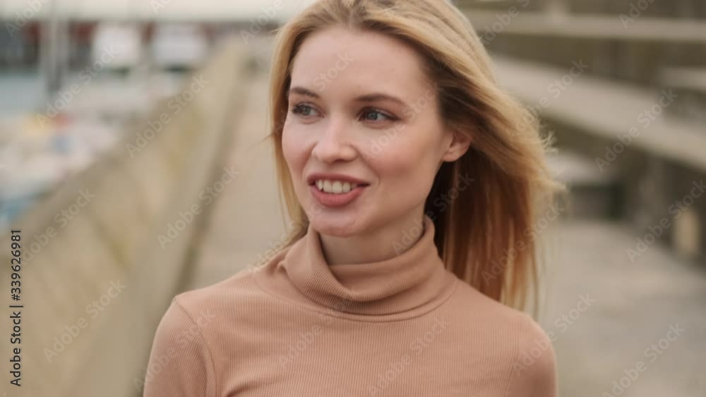 Close up shot of beautiful smiling blond girl happily walking along seafront Close up shot of beautiful smiling blond girl happily walking along seafront
