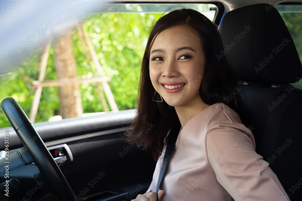 Driver Asian woman putting on safety seat belt while sitting inside the car before driving and take a safe journey Driver Asian woman putting on safety seat belt while sitting inside the car before driving and take a safe journey