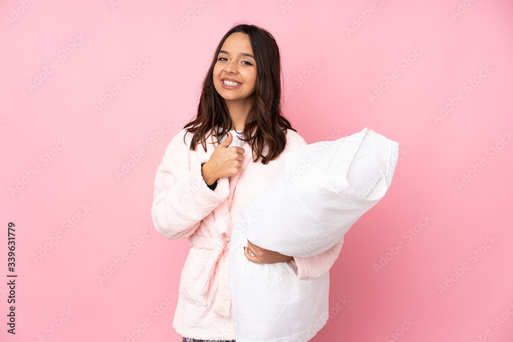 Young woman in pajamas isolated on pink background giving a thumbs up gesture Young woman in pajamas isolated on pink background giving a thumbs up gesture